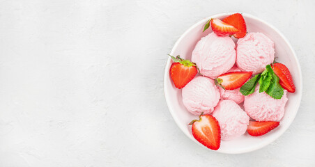 pink strawberry ice cream ball in a spoon in white bowl