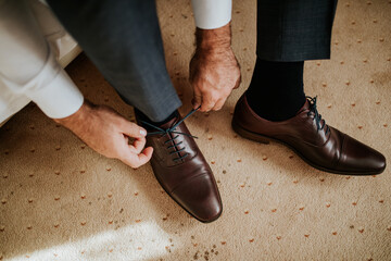 A close-up shot of a man tying his formal shoes, highlighting the detail and craftsmanship of the...