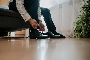 A close-up shot of a man tying his formal shoes, highlighting the detail and craftsmanship of the...