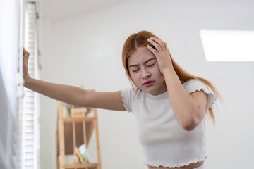 Young Woman Suffering from a Severe Headache at Home, Holding Her Head in Pain