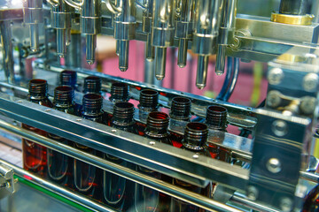 Glass bottles in a conveyor belt on a high quality automatic vertical filling machine. In the factory production line