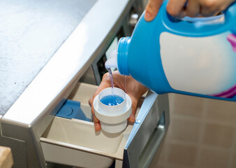 Women add laundry detergent to the washing machine