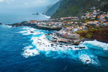 Fototapeta premium Natural lava swimming pools in Porto Moniz in Madeira island with big waves Atlantic ocean. Aerial view