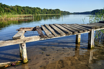 boards on a destroyed wooden pier on the lake shore