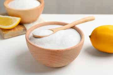 Baking soda and lemons on white wooden table, closeup