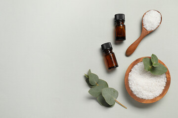 Aromatherapy products. Bottles of essential oil, sea salt and eucalyptus leaves on grey background, flat lay. Space for text