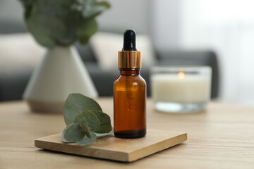 Aromatherapy. Bottle of essential oil and eucalyptus leaves on wooden table