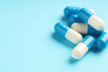 Many antibiotic pills on light blue background, closeup. Medicinal treatment
