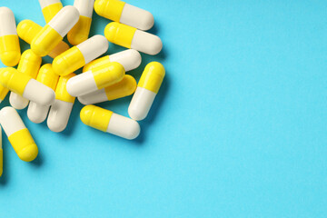 Many antibiotic pills and space for text on light blue background, top view. Medicinal treatment