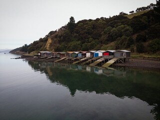 Historic colorful wooden boat sheds on Duvauchelle Bay shore in Akaroa Harbour, Banks Peninsula, Canterbury, New Zealand