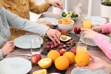 Friends eating vegetarian food at wooden table indoors, closeup