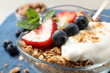 Tasty granola with berries, yogurt and mint on grey table, closeup