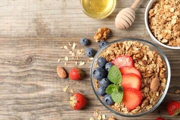 Tasty granola with berries, nuts and mint on wooden table, flat lay. Space for text