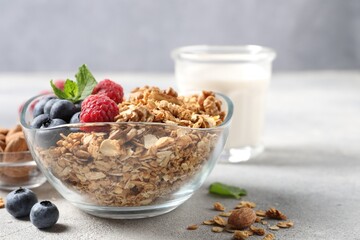 Tasty granola with berries, nuts and mint on grey table. Space for text