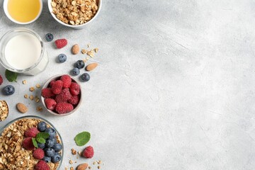 Tasty granola with berries, nuts and mint on grey table, flat lay. Space for text