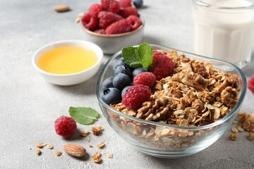 Tasty granola with berries, nuts and mint on grey table
