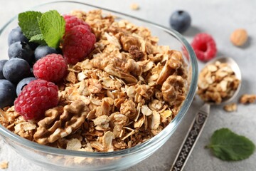 Tasty granola with berries, nuts and mint on grey table, closeup