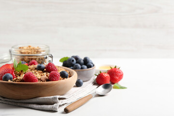 Tasty granola with berries, nuts and mint on white table. Space for text