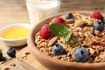 Tasty granola with berries, nuts and mint on wooden table, closeup