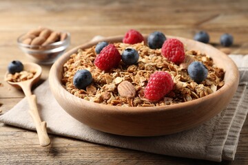 Tasty granola with fresh berries and nuts on wooden table