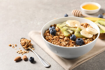 Tasty granola with fresh fruits on grey table. Space for text