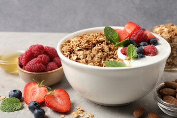 Tasty granola with berries and yogurt in bowl on grey table, closeup