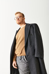 Fototapeta premium Handsome man in stylish long coat and glasses posing confidently.