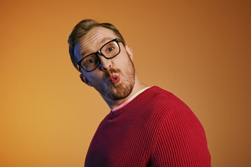 A man with glasses and stylish attire making a comical expression.
