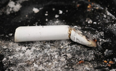 Close up cigarette butt in black ashtray