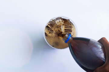 Human hand pours soda into a glass,Human hand pouring cola from plastic bottle into glass with ice cubes. Isolated on white background. 