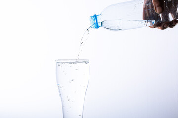 Human hand pouring drinking water into a glass, isolated on white background,Man hand holding plastic water bottle and poring water into glass on white background