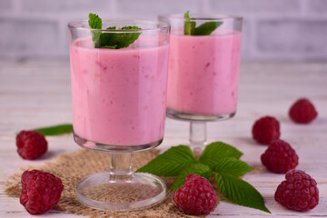 Raspberry smoothie with mint on a white wooden background.
