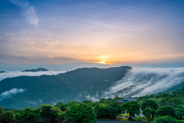 At dawn, the peaceful waterfall of clouds gradually disperses during sunrise. View of the mountains surrounding Emerald Reservoir. Xindian District, Taiwan.