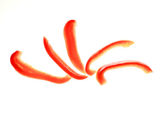 A close up of red peppers. The peppers are sliced and arranged in a row on white background. Food...