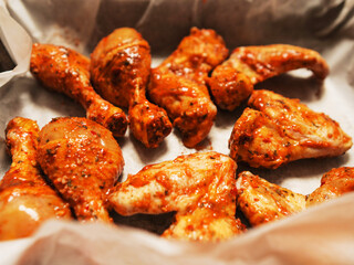 Asian style marinated chicken drumsticks and wings on cooking paper in a metal tray ready to be cooked. Fine poultry product for oven or barbecue. Simple popular traditionally meal.