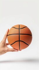 Fototapeta premium Close-up of a hand holding a basketball against a white background. Perfect for sports and fitness-related content.