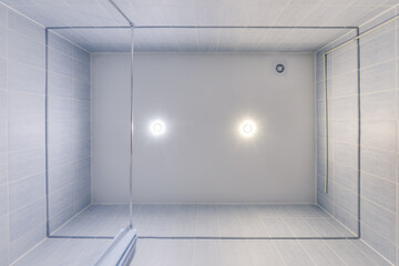 suspended ceiling with halogen spots lamps and drywall construction in empty room in apartment or house. Stretch ceiling white and complex shape.