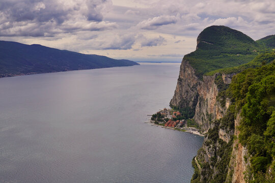 Blick von der Schauderterrasse, Terrazza del Brivido, auf den kleinen Ort Campione del Garda unterhalb einer steilen Felsenklippe am Ufer des Gardasees, Italien.
