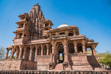 Fototapeta premium Ancient Indian Temples of structure featuring intricate carvings and vibrant floral foreground, Mandore Gardens, Jodhpur, Rajasthan, India