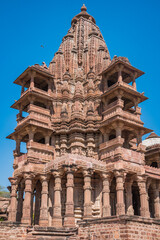 Obraz premium Ancient Indian Temples of structure featuring intricate carvings and vibrant floral foreground, Mandore Gardens, Jodhpur, Rajasthan, India