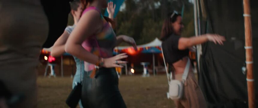 Three happy young women dancing together at a festival