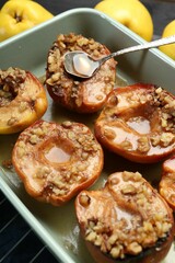 Tasty baked quinces with nuts and honey in dish on grid, closeup