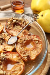 Tasty baked quinces with walnuts and honey in bowl on table, closeup