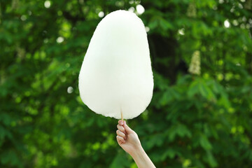 Woman holding sweet cotton candy outdoors, closeup