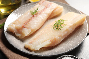 Pieces of raw cod fish and dill on table, closeup