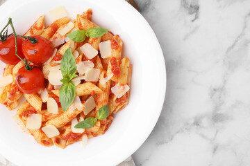 Tasty pasta with tomato sauce, cheese and basil on white marble table, top view. Space for text