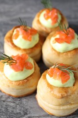 Delicious puff pastry with avocado cream, salmon and dill on grey table