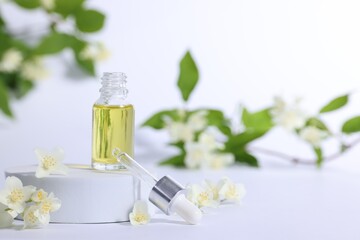 Presentation of essential oil in bottle and beautiful jasmine flowers on white background