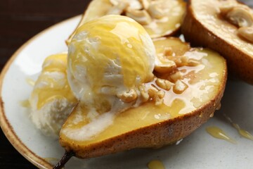 Delicious baked pears with nuts, ice cream and honey on plate, closeup