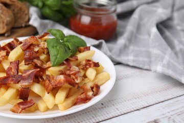 Delicious French fries with bacon and basil on wooden rustic table, closeup. Space for text